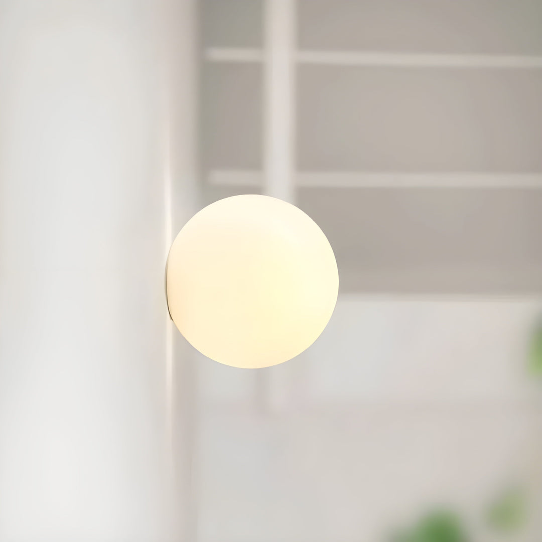 Frosted glass globe wall lamp illuminated in a dark bedroom setting for ambient glow