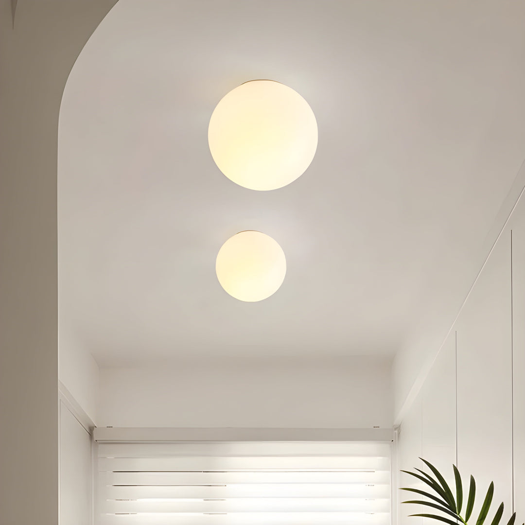 Close-up of the frosted glass globe on a sleek brass wall sconce arm