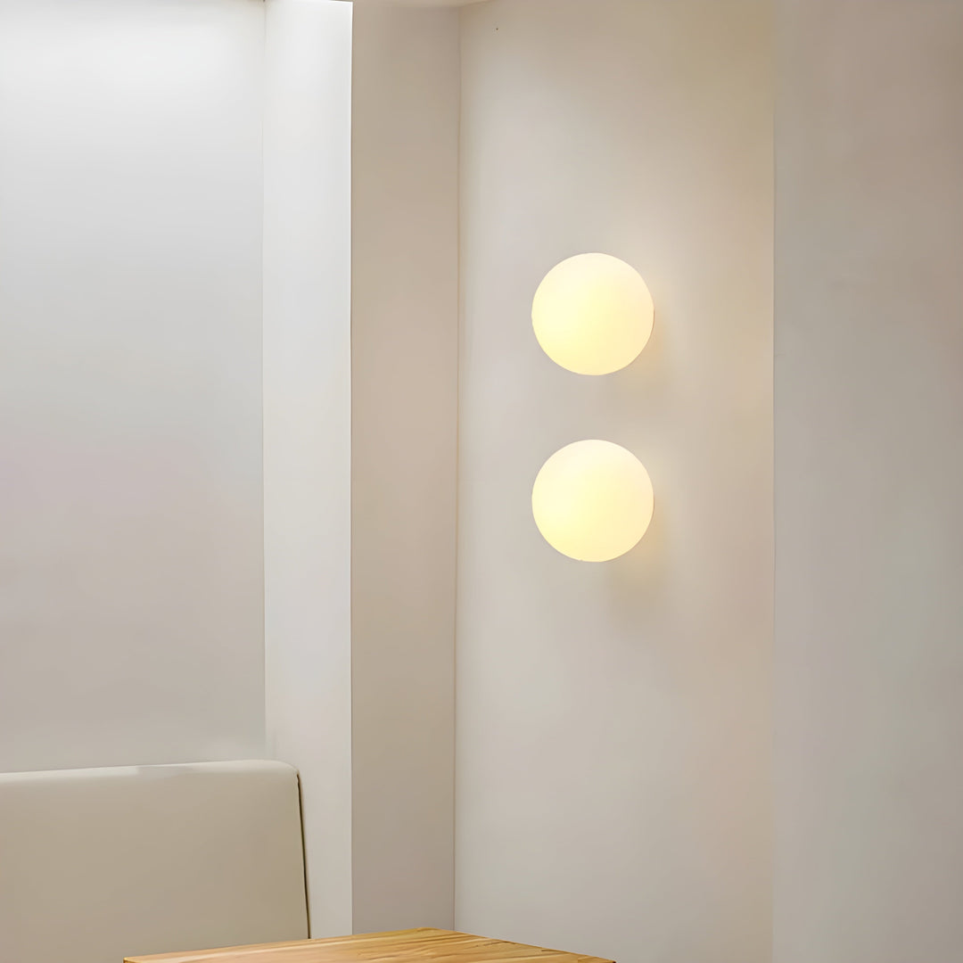Modern round frosted glass wall lamps emitting a soft warm glow in a contemporary minimalist interior setting