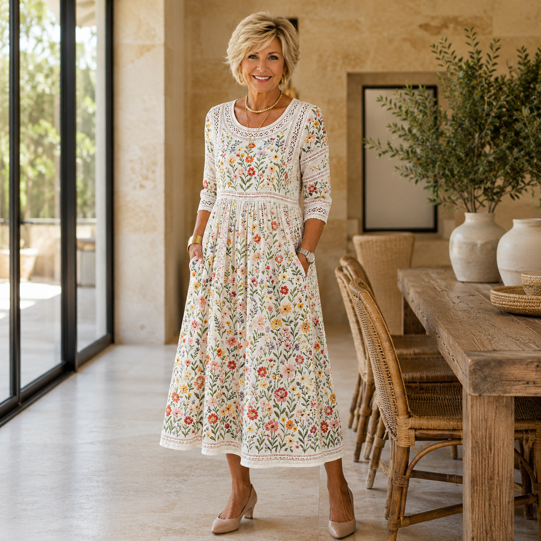 Woman wearing a floral embroidered midi dress with pockets standing in a rustic room