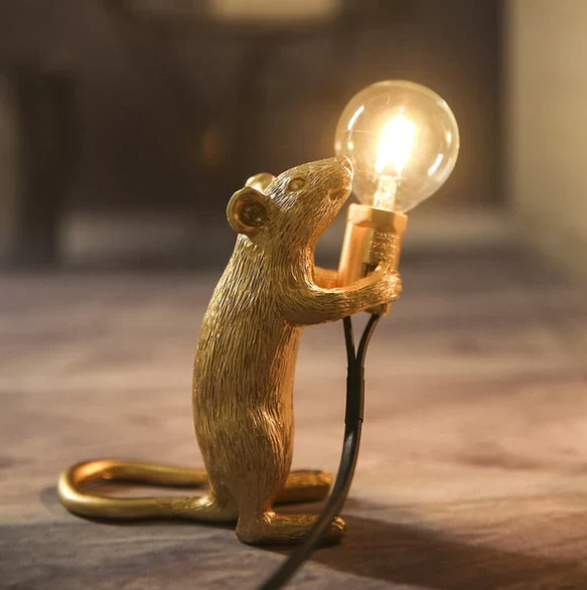 Gold standing mouse table lamp holding a light bulb on a surface