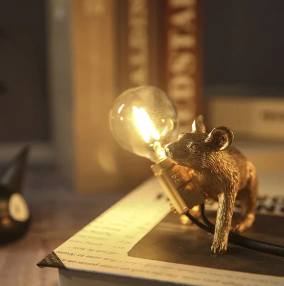Gold crawling mouse table lamp illuminating a desk area