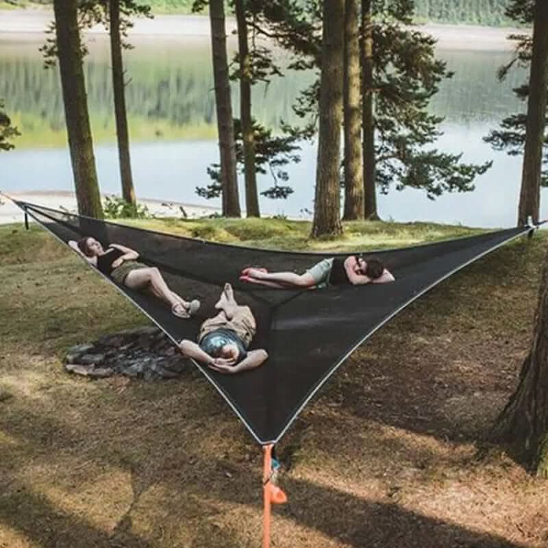 Group of people relaxing on a black multi-person camping hammock by a lake