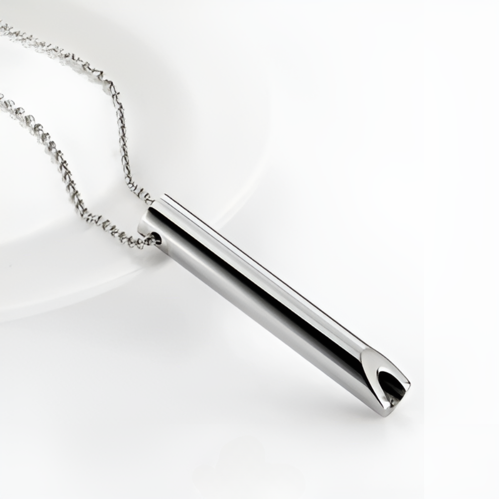 Silver anti-smoking breathing necklace pendant on a white plate