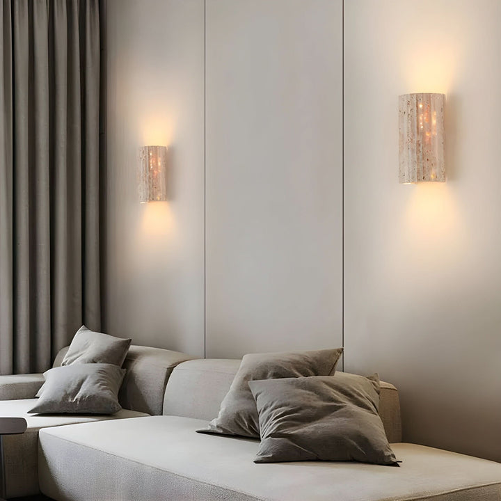 Two natural stone LED wall sconce lights mounted on a panelled wall above a contemporary sofa