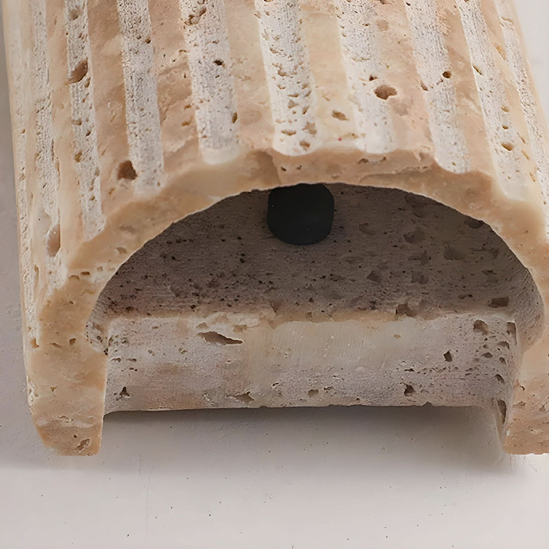 Close-up view of the minimalist stone light fixture illuminating a cozy living room wall.