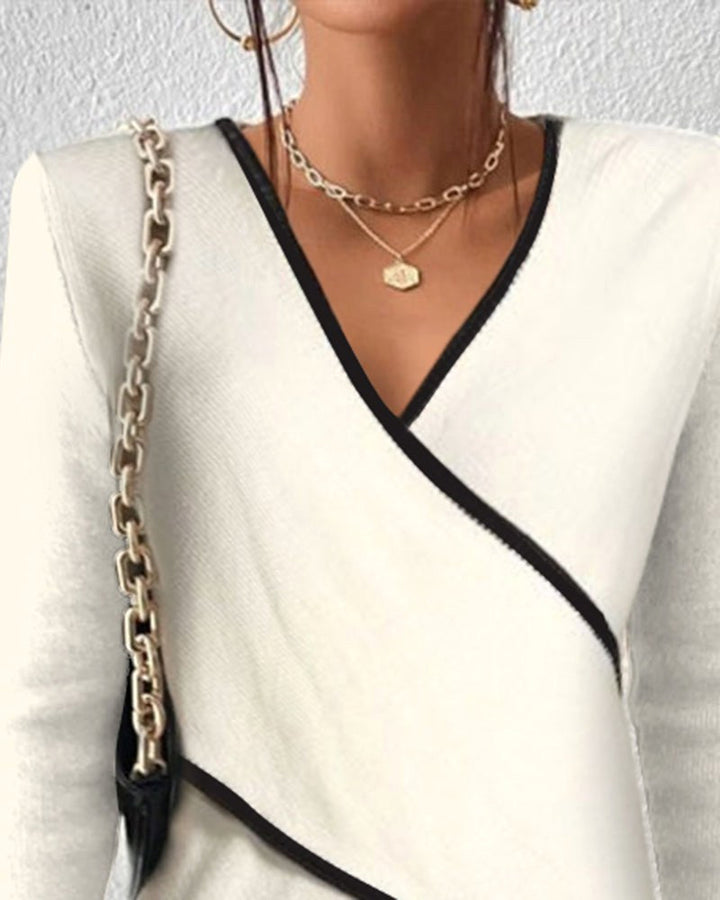 Close-up of the V-neckline and layered collar design on the white sweater