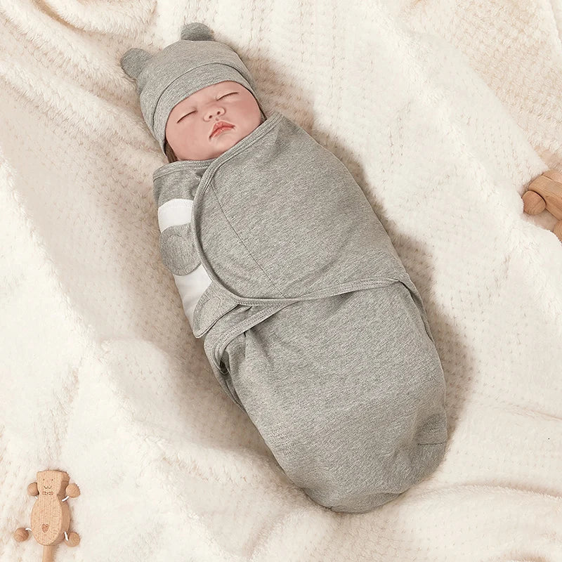Cozy gray newborn swaddle wrap and matching beanie hat on a soft blanket