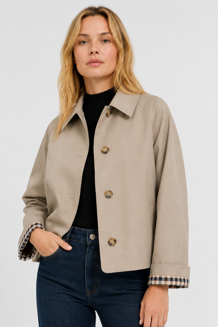 Front view of a woman wearing a lightweight beige jacket with turned-back checked cuffs