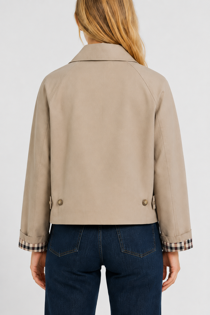 Back view of a woman wearing a relaxed fit beige jacket with side button tabs