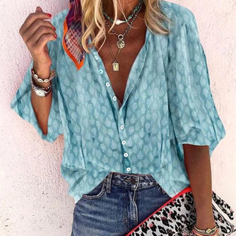 Woman wearing light blue button-front blouse with layered necklaces and denim jeans