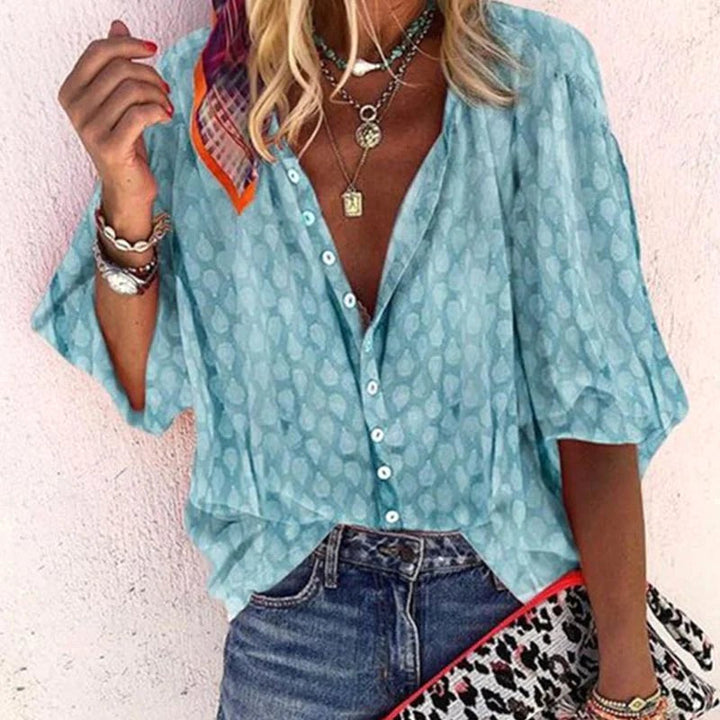 Woman wearing light blue button-front blouse with layered necklaces and denim jeans