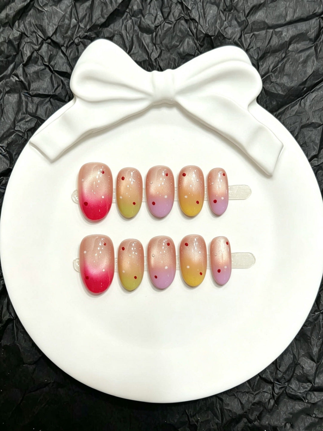 Ombre gradient press-on nail set displayed on a white decorative dish