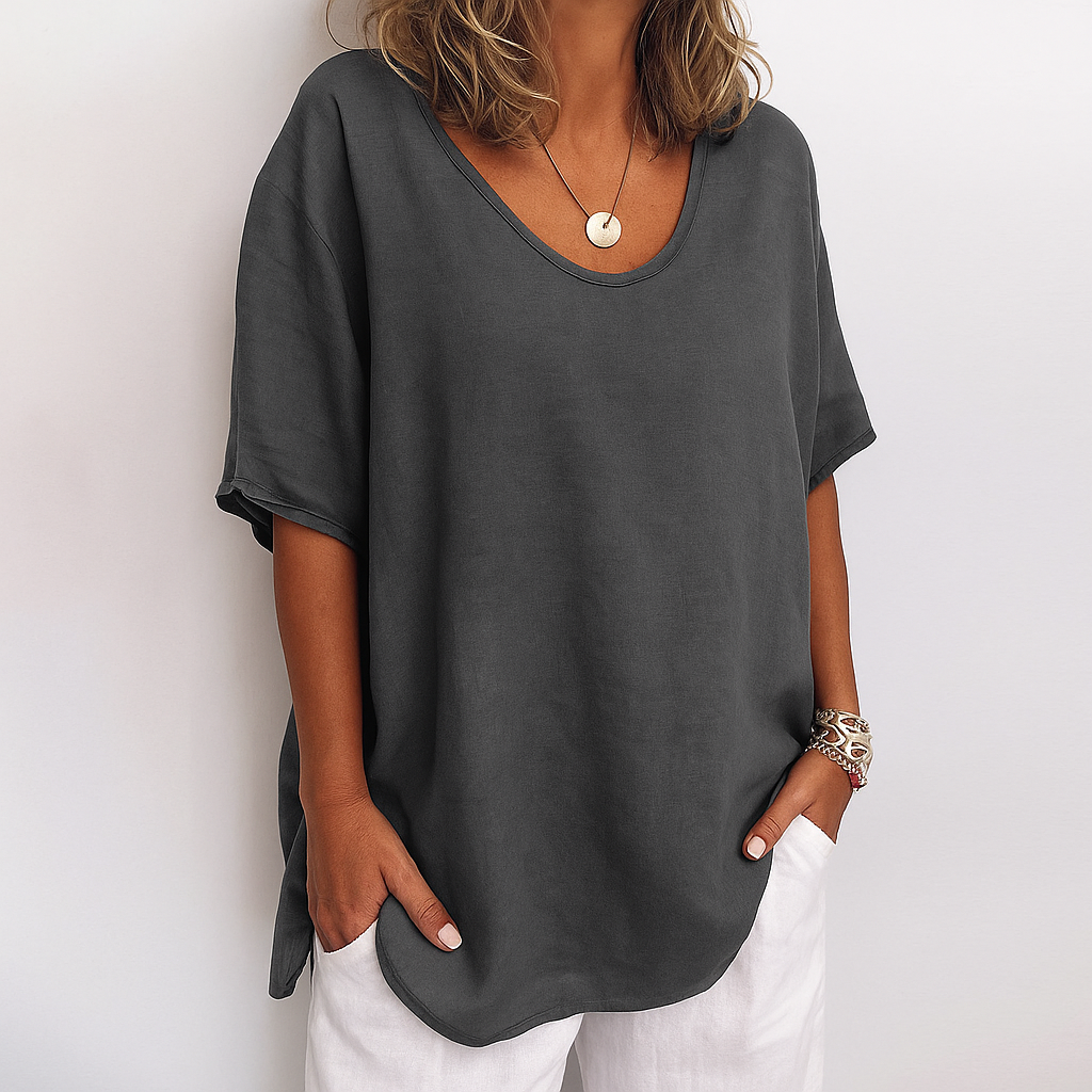 Woman wearing a dark grey relaxed fit short sleeve casual top with white trousers