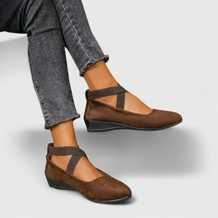 Brown orthopedic wedge sandals worn on feet with dark jeans