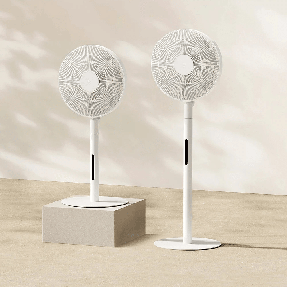 Two white oscillating pedestal fans displayed on a podium with natural lighting