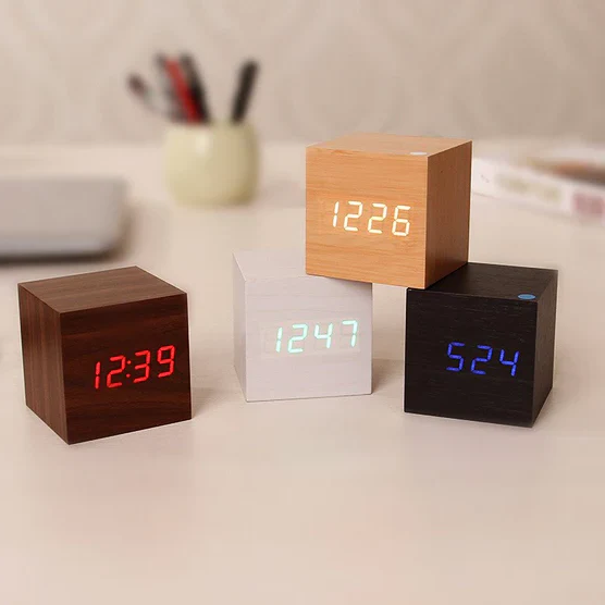 Minimalist wooden alarm clock with LED display showing temperature and time on a nightstand