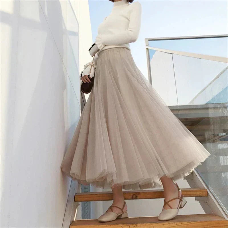 Woman wearing beige high waist pleated maxi skirt with white top on stairs
