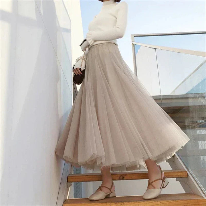 Woman wearing beige high waist pleated maxi skirt with white top on stairs