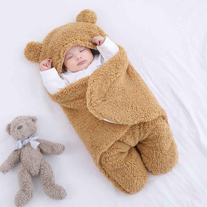 Baby sleeping soundly wrapped in a caramel bear ear wrap blanket