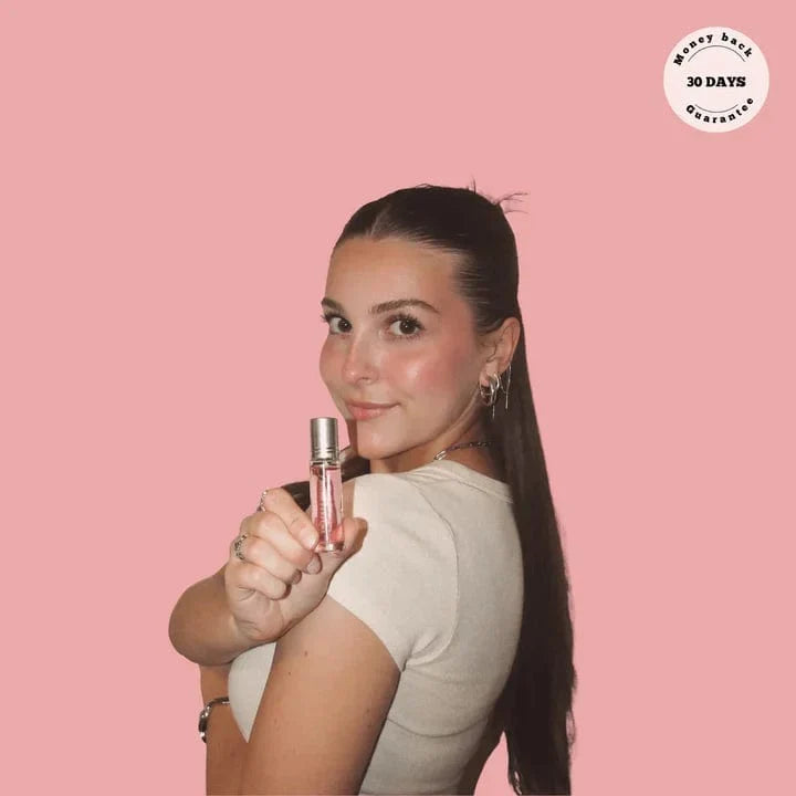 Smiling woman holding up Phero Perfume bottle