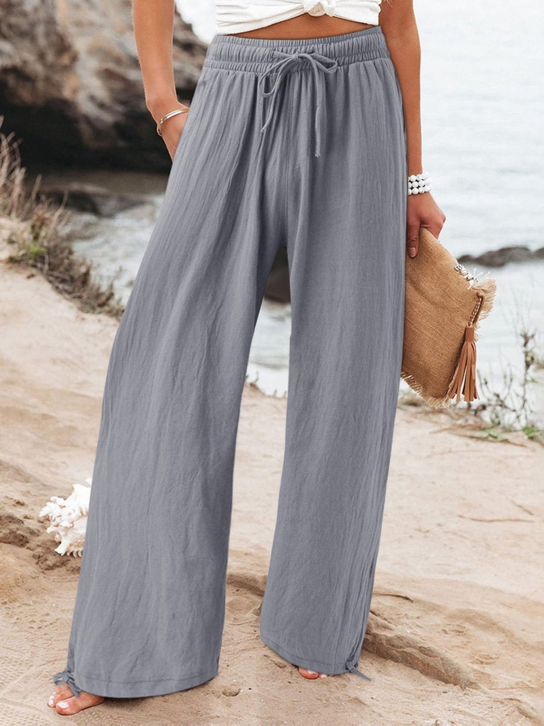 Model wearing grey relaxed wide leg pants with a drawstring waist outdoors