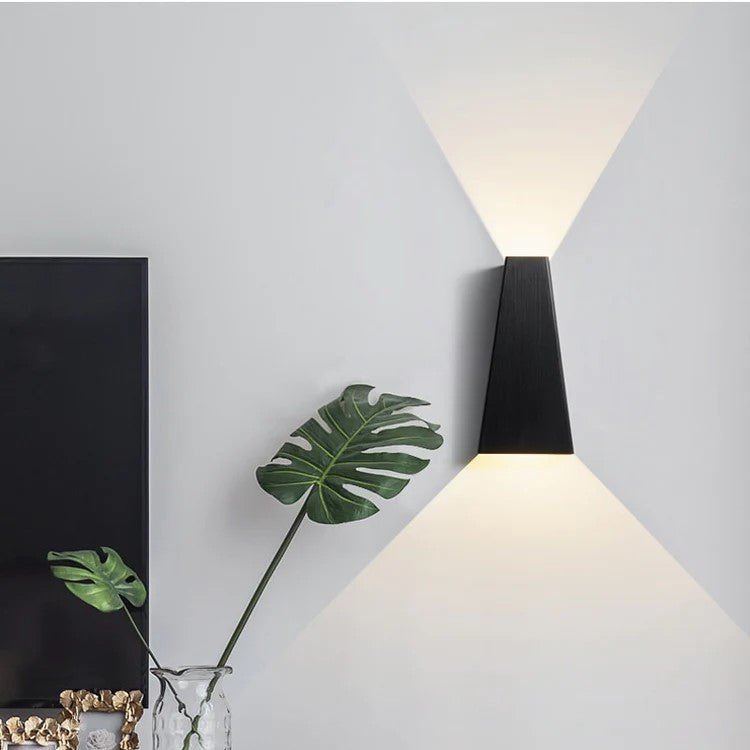 Modern black LED wall lamp casting upward and downward light beams on a living room wall