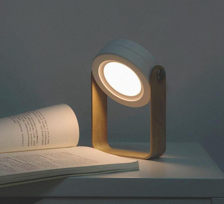 Portable LED camping lantern adjusted into a reading desk lamp position over an open book