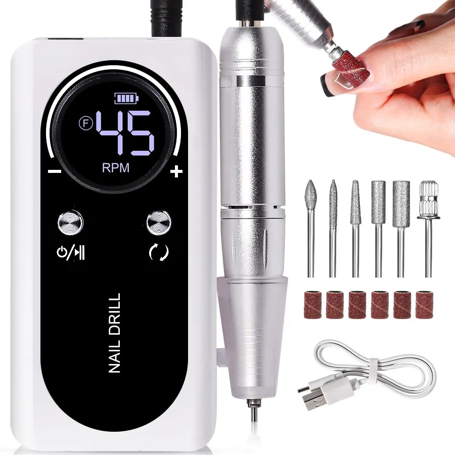 White electric nail file with handpiece, drill bits, and charging cable laid out on a white background