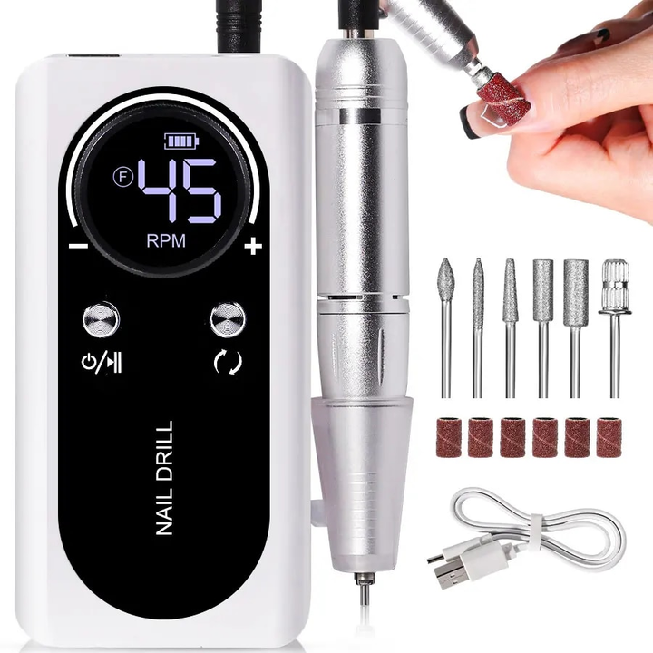 White electric nail file with handpiece, drill bits, and charging cable laid out on a white background