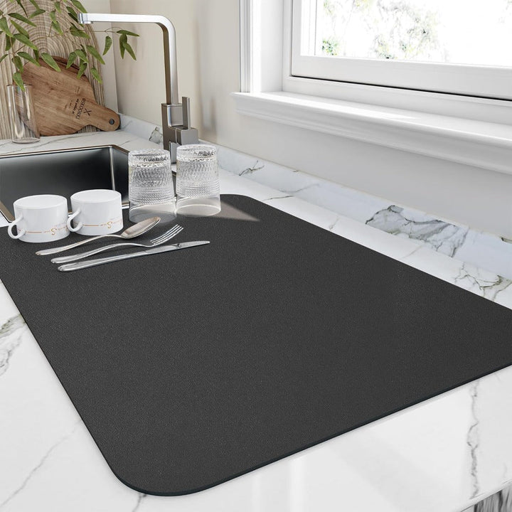 Black quick dry kitchen dish mat placed on a marble countertop next to the sink