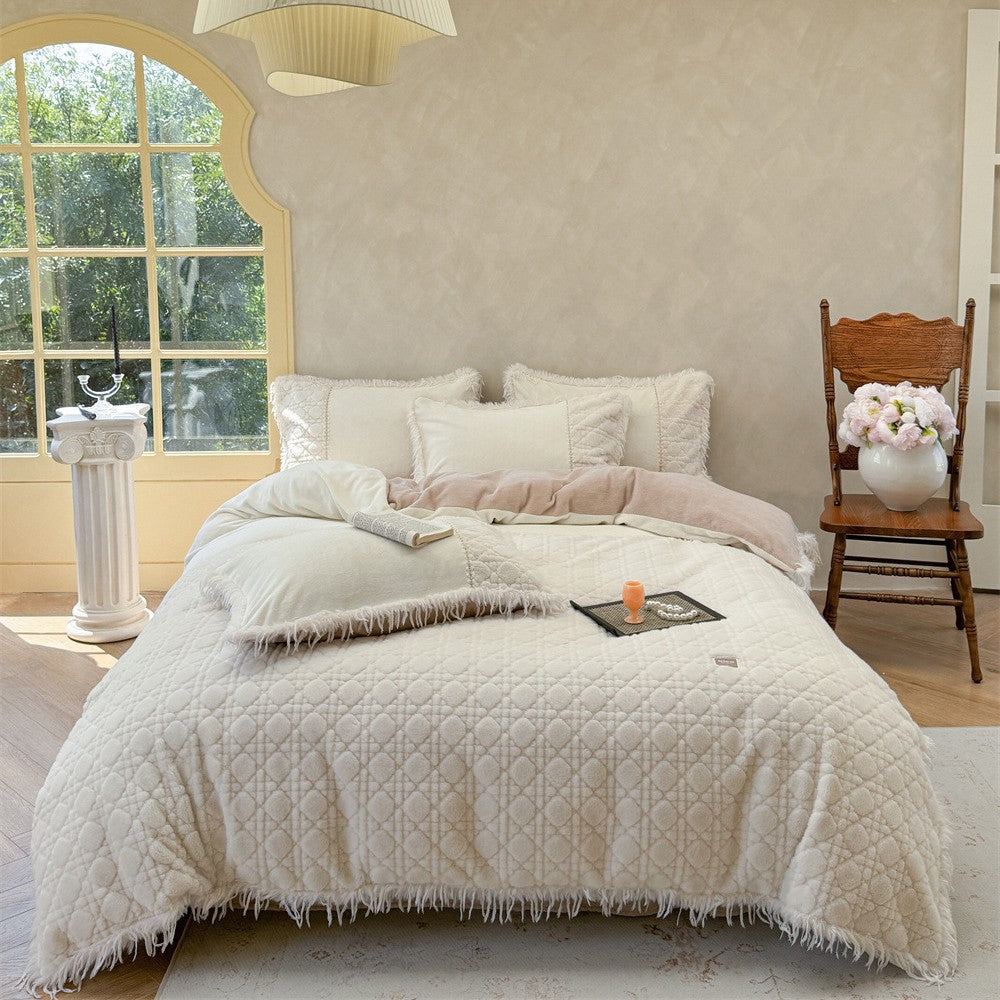 White quilted bedding set with decorative fringe details arranged in a bright bedroom