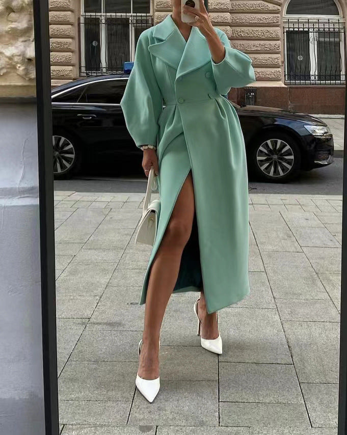 Woman wearing a mint green double-breasted long coat holding a white handbag