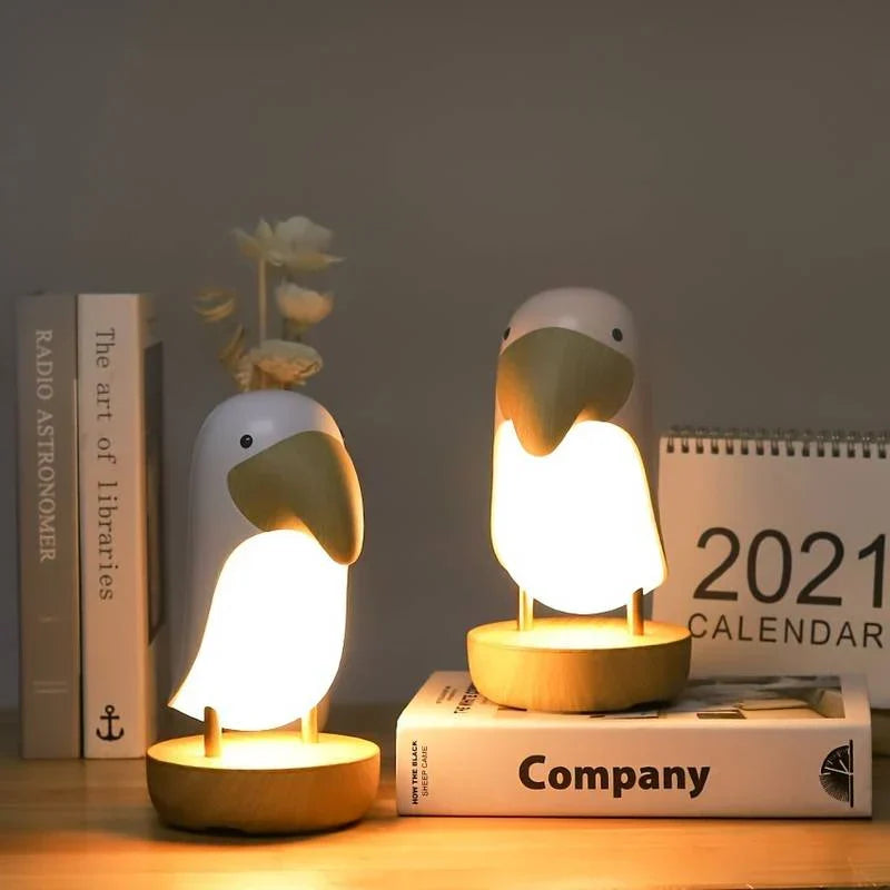 Two woodpecker nightlights glowing on a wooden table next to books and a calendar
