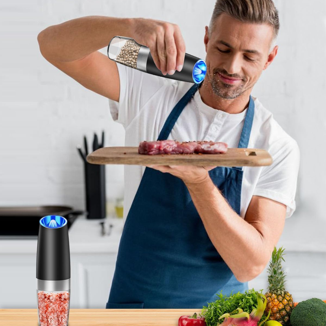 Man seasoning meat with electric pepper mill in kitchen