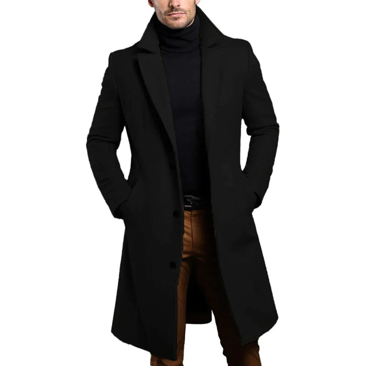 Man wearing a black classic long winter coat in a clean studio setting