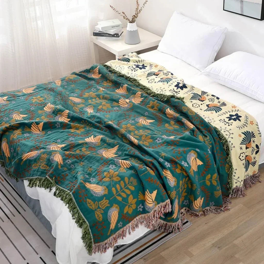 Turquoise-Beige Nordic bird blanket draped elegantly over a white bed in a bright bedroom