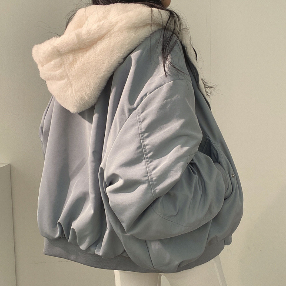 Back view of a woman wearing a light blue winter jacket highlighting the cozy hood
