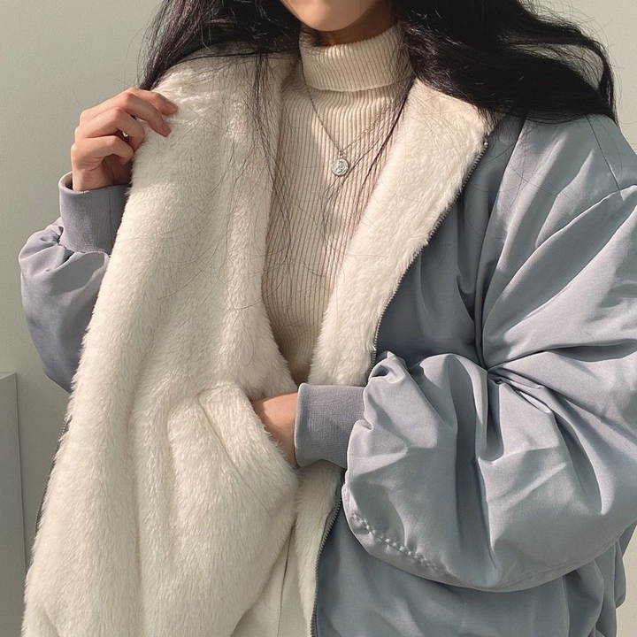 Close-up of a woman wearing a light blue and white reversible winter jacket with a turtleneck