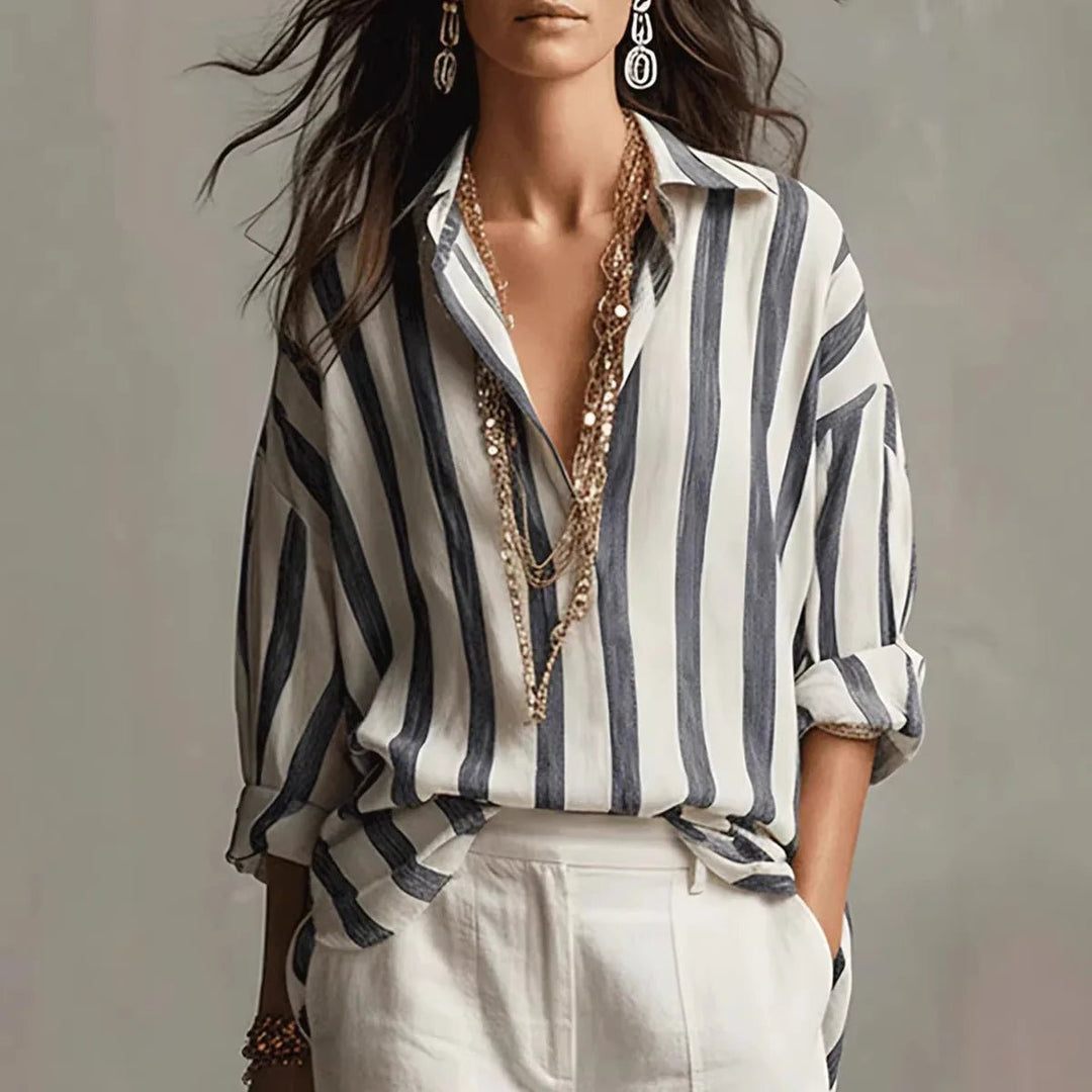 Woman wearing black and white striped long sleeve collared blouse with layered necklaces