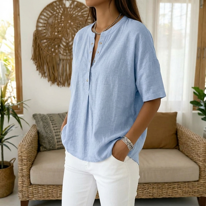 Woman wearing a light blue relaxed fit henley blouse with white jeans