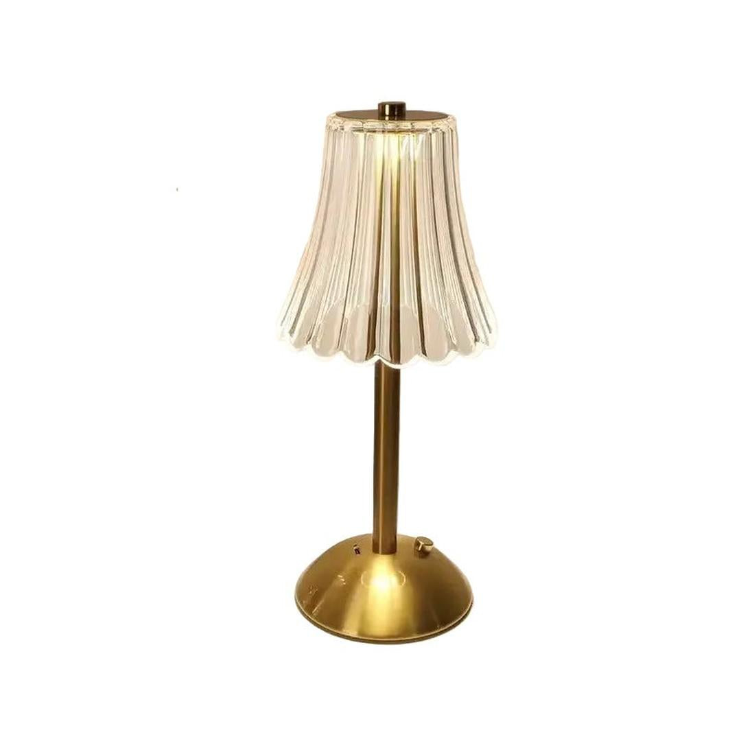 Gold round base table lamp with transparent wavy shade standing on a surface