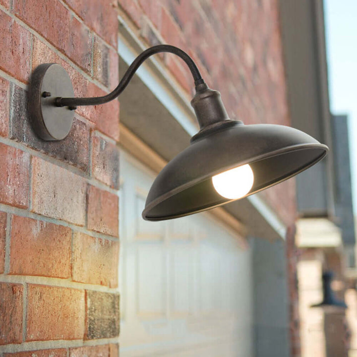 Close-up of the antique brass outdoor wall lamp mounted securely on a red brick exterior wall