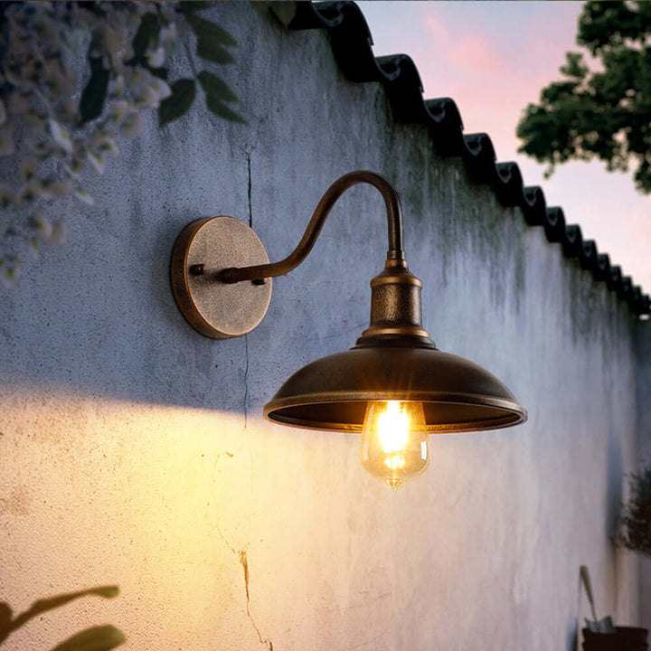 Illuminated rustic outdoor wall lamp casting a warm glow on a stone courtyard wall at dusk