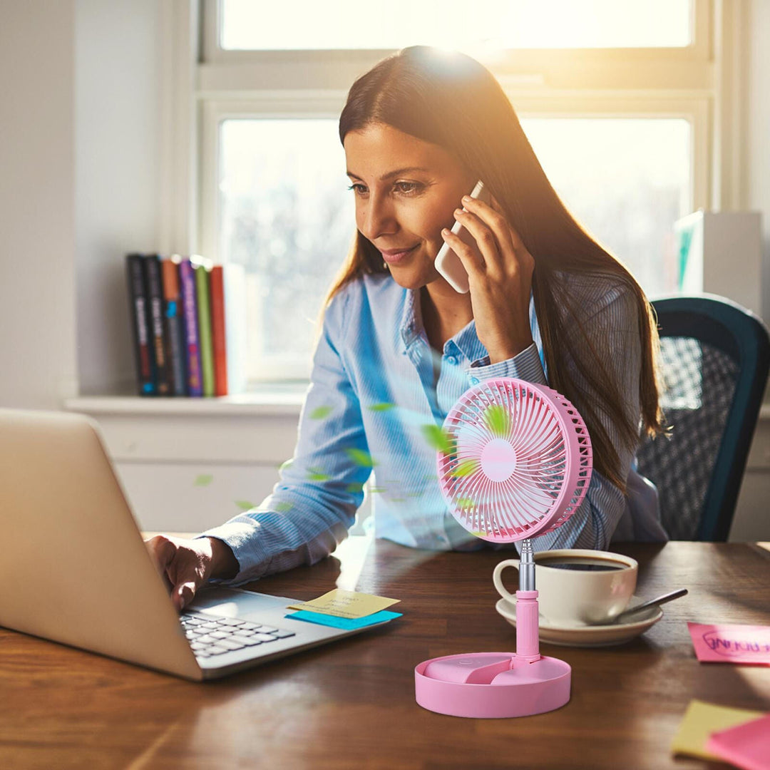 Woman using a pink portable folding fan at her desk