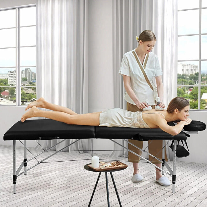 Professional portable aluminium massage table set up in a bright room with therapist