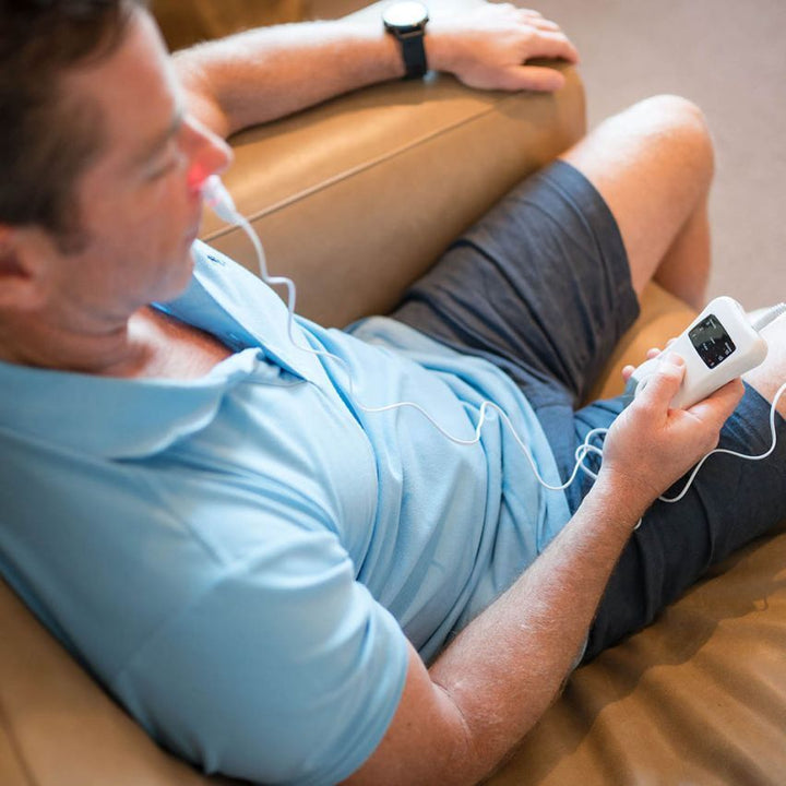 Man sitting comfortably while using the nasal allergy treatment device