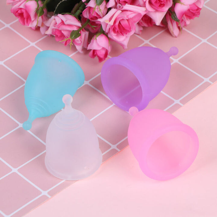 Colorful medical silicone menstrual cups arranged on a pink background