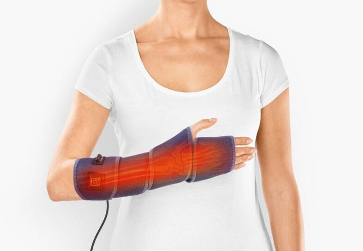 Person wearing an electric heating wrap on the wrist and lower arm for targeted relief