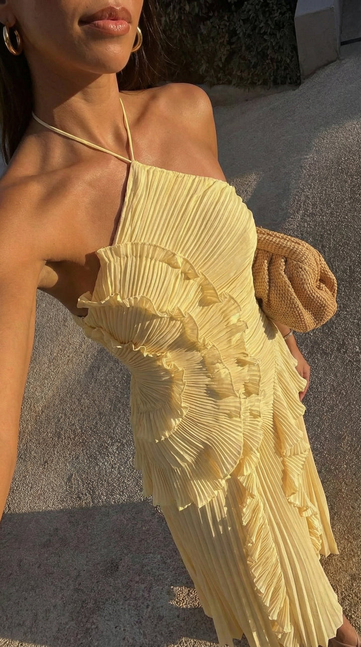 Close up view of the pleated texture and halter neckline of the yellow dress.